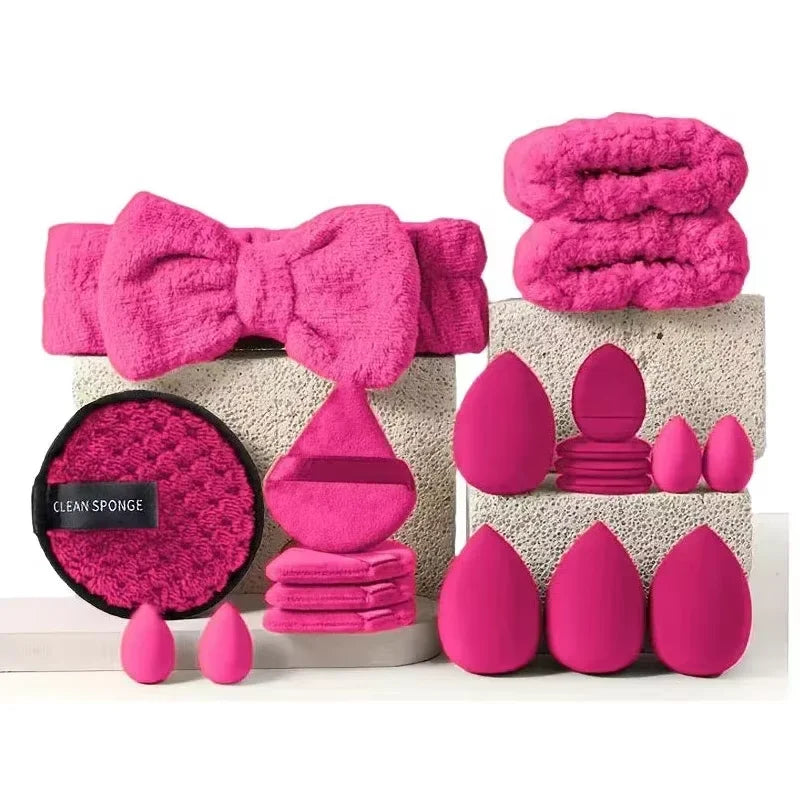 A collection of pink fuzzy makeup brushes and sponges displayed on a white surface.