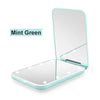 A mint green portable LED magnifying makeup mirror shown open and closed.