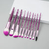 A set of ten professional makeup brushes with pink and purple glitter handles and pink bristles.