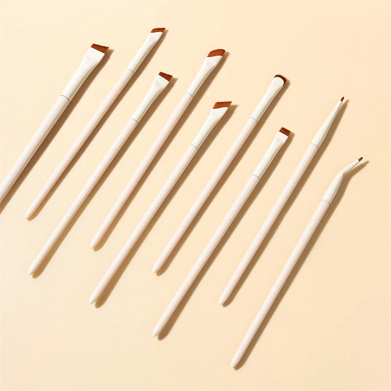 A set of precision angled eyeliner and eyebrow makeup brushes displayed diagonally on a light beige background.
