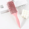 Peigne professionnel curly rose avec poils roses à côté d'un accessoire pour cheveux blanc.