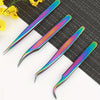 Four precision stainless steel eyelash tweezers with iridescent gradient tips resting on a dark textured surface.
