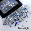 A pile of iridescent and blue glass rhinestones for nail art and DIY crafts under moonlight lighting.