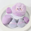 Un ensemble de puffs de poudre brodés en tons lavande et lilas présentés sur une assiette blanche.