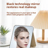 A portable folding cosmetic mirror with a pink casing is shown next to a lamp and skincare products.