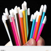 A hand holds a variety of disposable lip brushes with nylon applicator wands in various colors.