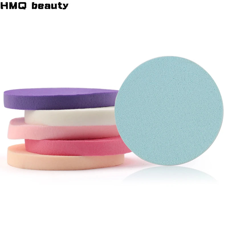 A stack of colored makeup sponge puffs in purple, white, pink, and peach tones.