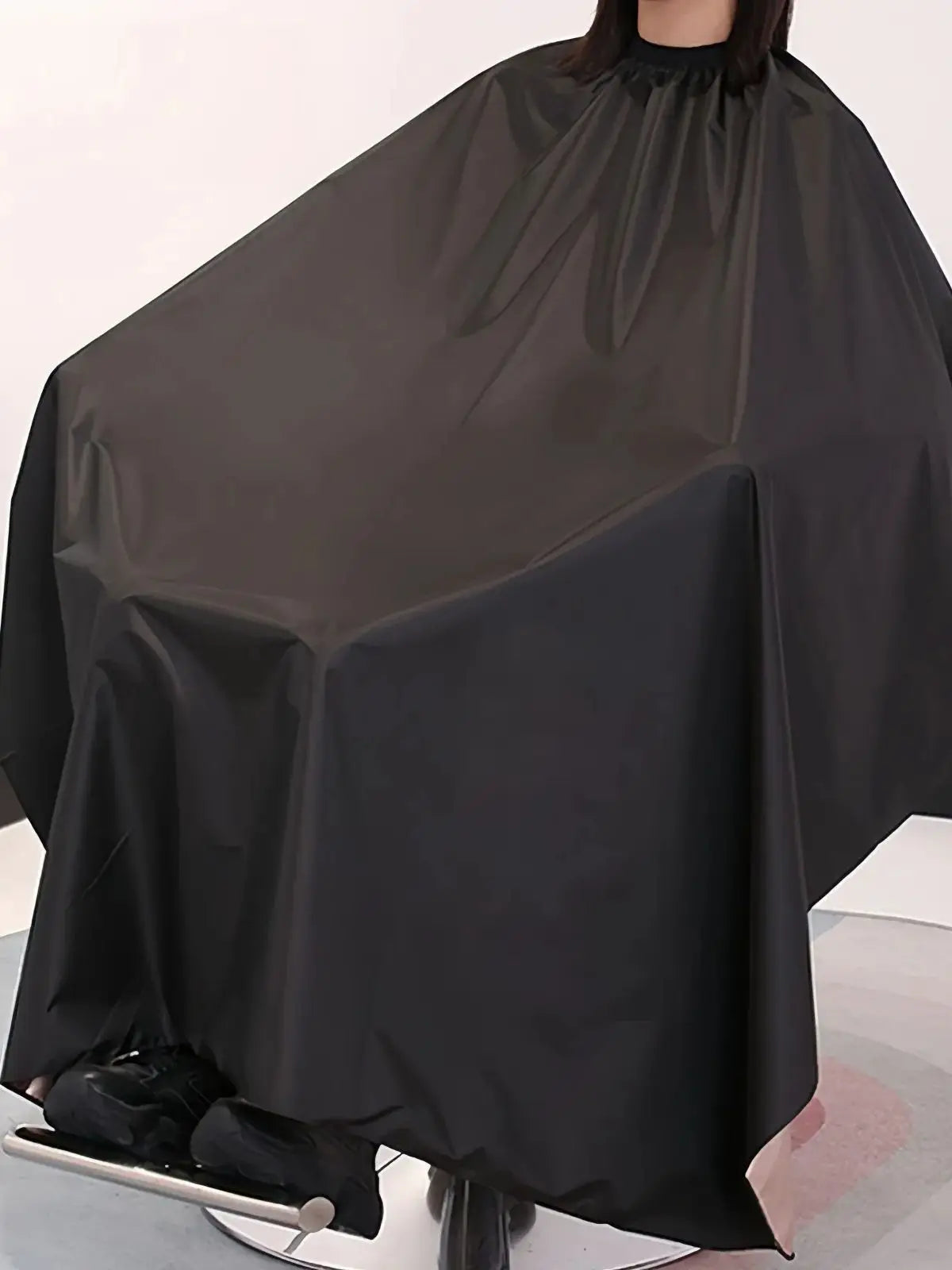 Un tablier de coiffure noir professionnel drapé sur un mannequin.