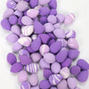 A collection of purple and pink reusable expandable makeup sponges.