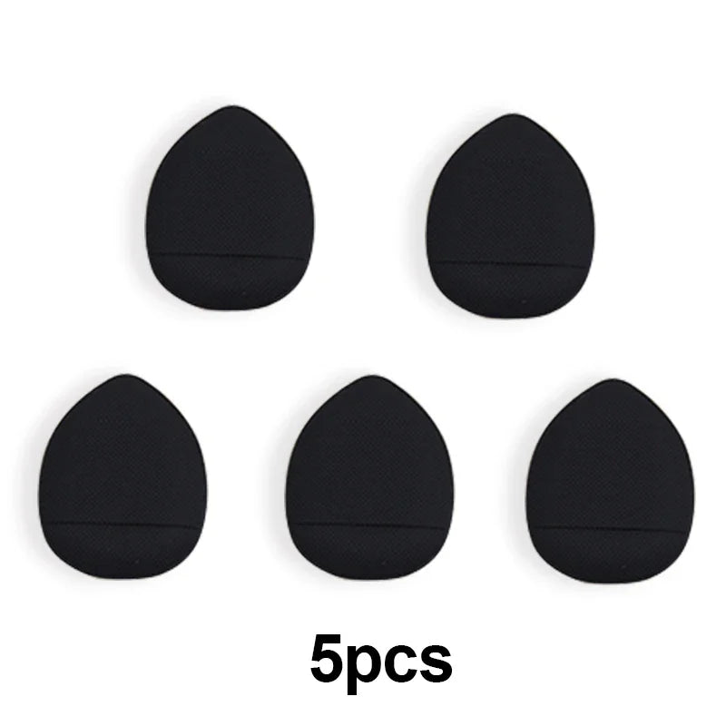 Cinq éponges de fondation noires miniatures, disposées en ligne et en colonne.