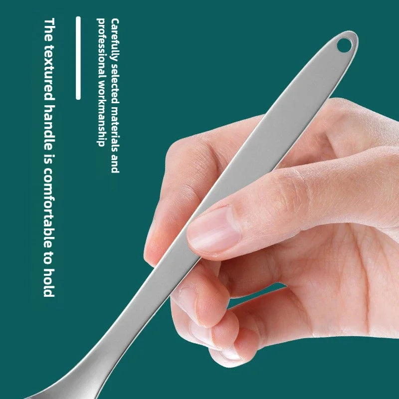 Une main tient un rasp à langue en acier inoxydable sur un fond vert foncé.