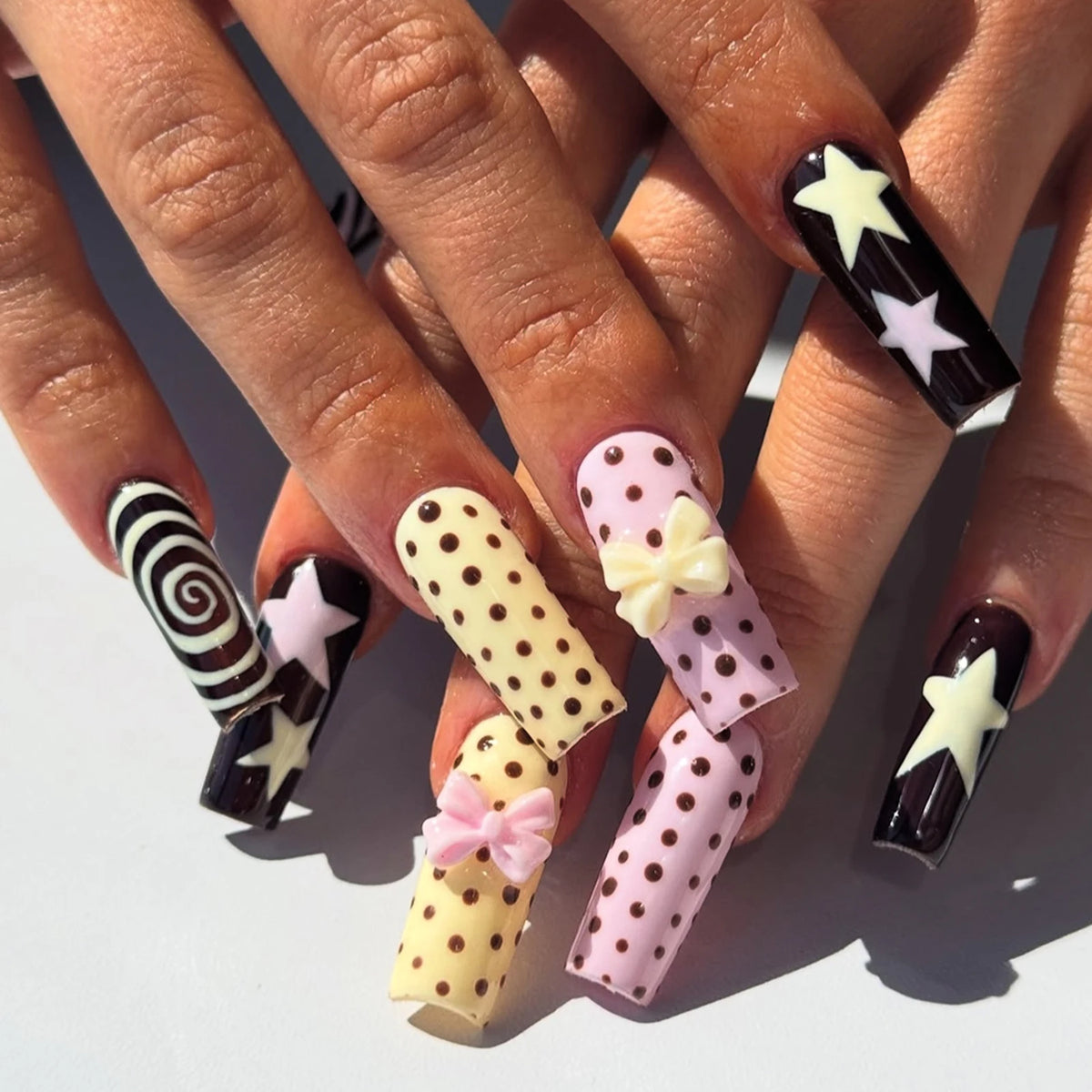 Press-on nails featuring a blue and brown French wave design with star accents on a hand.