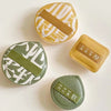 A set of three air cushion makeup puffs in olive green and beige with storage boxes.