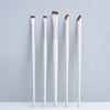 A set of five precision eyeliner application brushes with white handles and brown tips displayed against a light gray backgro