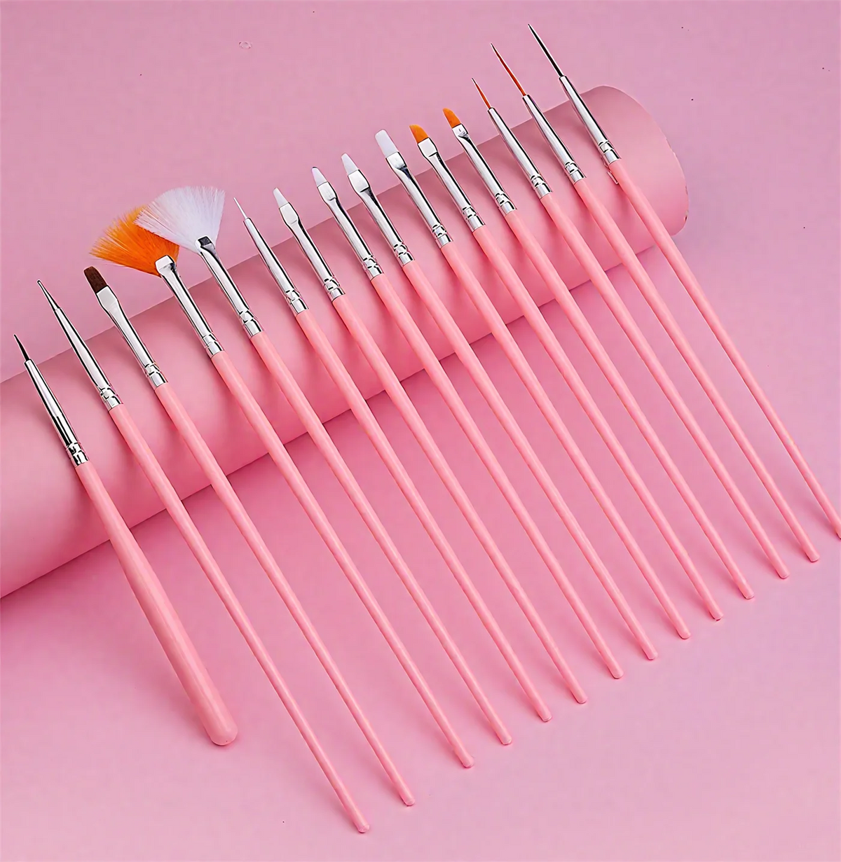 A collection of pink professional nail art brushes and tools arranged diagonally on a pink background.