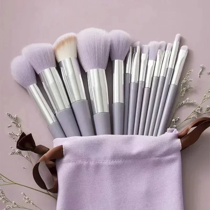 A collection of 22 professional makeup brushes with synthetic bristles standing upright in a lavender fabric holder.