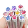 Una mano sostiene un set de brochas reutilizables para pestañas con diversos colores de purpurina, incluyendo rosa, púrpura, 