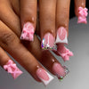 A close-up of a hand displaying nude pink press-on nails with leopard print accents and 3D charms.