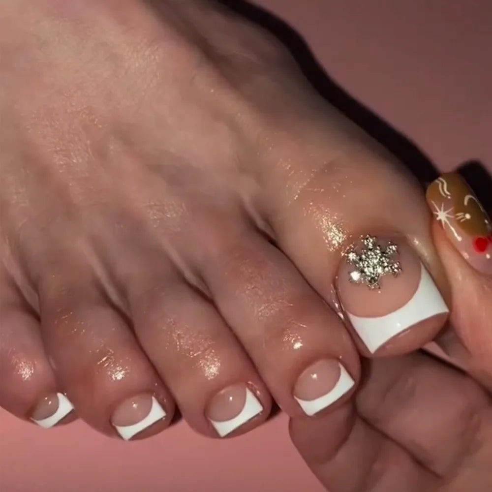A close-up of a hand displaying press-on fake nails with short square French tips and gold accents.
