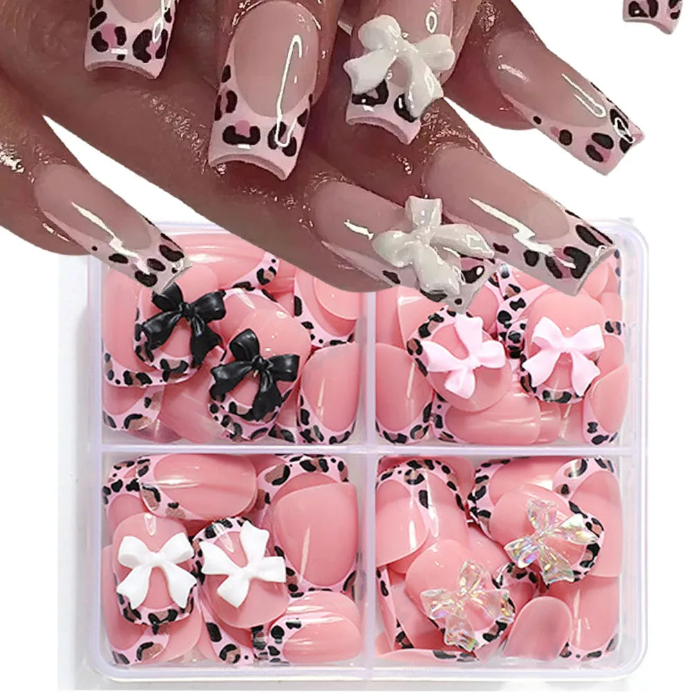 A hand displays long press-on nails with a pink and black leopard print design.