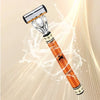 An orange-handled six-blade manual razor with a silver head and lubricating strip, set against a translucent background.