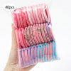 A hand holds a clear plastic package containing 40 pink and purple beauty puffs.