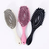 Three hair styling combs in shades of gray, pink, and black with various bristles.