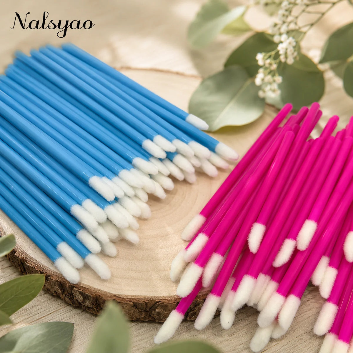 A close-up photo shows a set of disposable lip applicator brushes in blue and pink, arranged diagonally on a wooden surface.