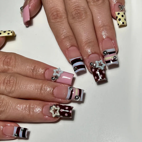 Press-on nails featuring a blue and brown French wave design with star accents on a natural nail bed.