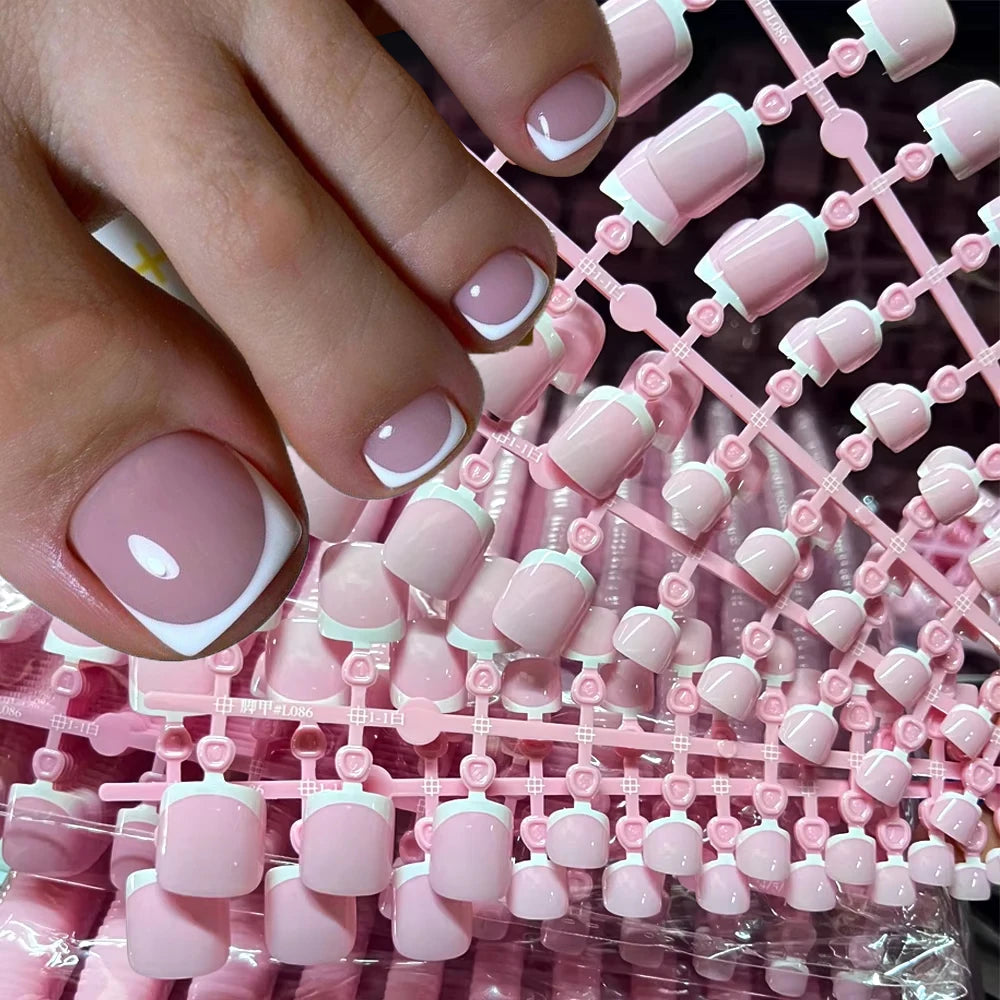 Close-up of a hand displaying pink French press shaped nails with white accents on a pink background.