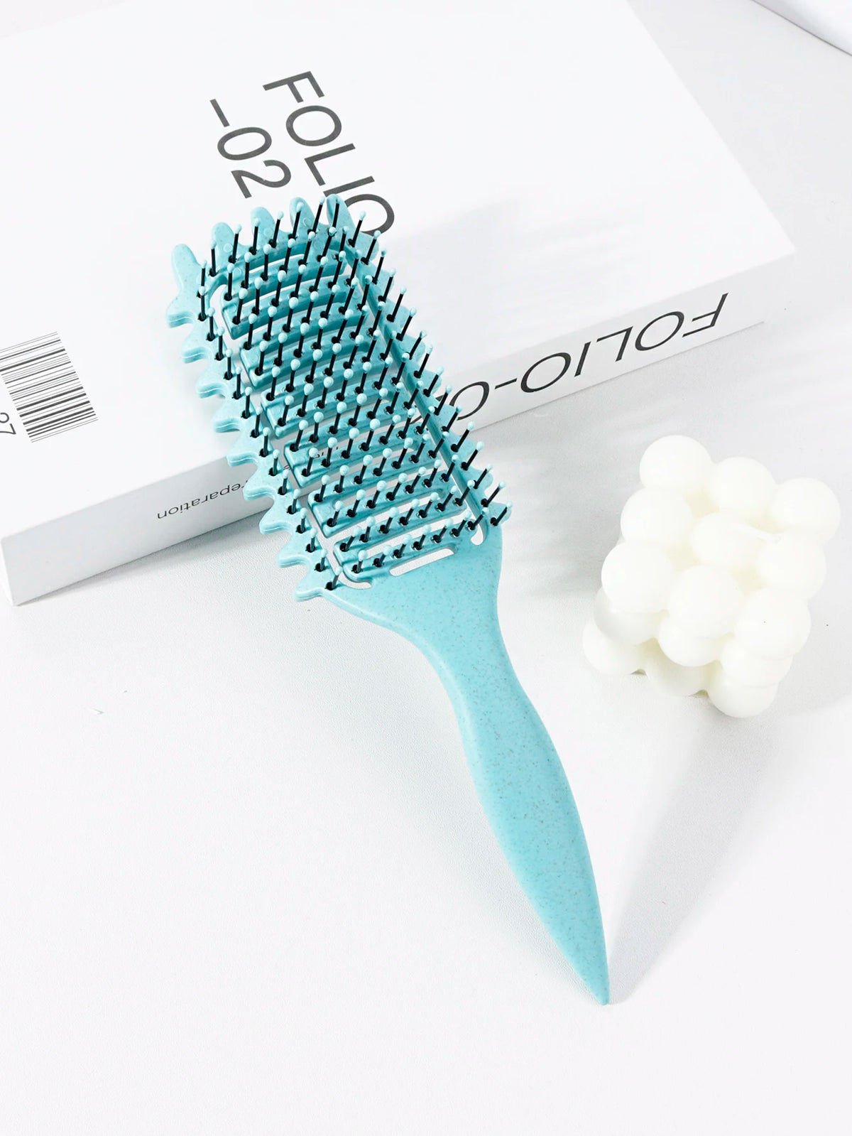 Peigne pour cheveux bouclés bleu clair professionnel avec dents sur fond blanc.