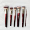 A set of four fluffy makeup brushes with pink bristles and gold ferrules displayed on a white surface.