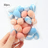 A hand holds a clear bag filled with 30 reusable expandable makeup sponges in various pastel blue and peach colors.