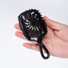 A hand is holding a black detangling hair comb with numerous teeth.