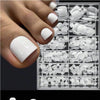 A hand displays a set of white reusable press-on acrylic false nails organized in a clear plastic case.
