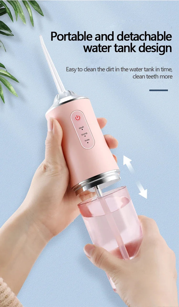 A hand holds a pink portable and detachable water tank design oral irrigator device.