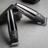 A silver and black professional rechargeable hair clipper is shown angled on a gray surface.