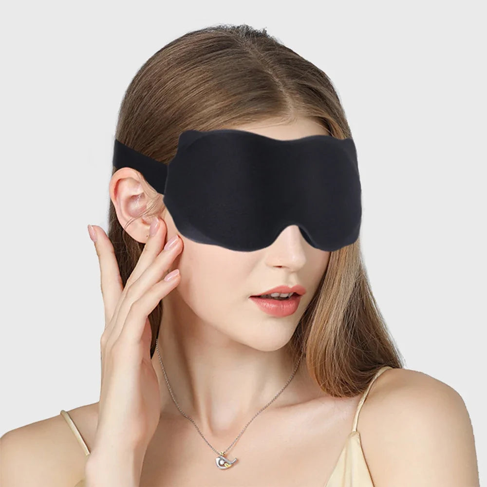 A woman is wearing a black 3D sleeping eye mask on her face.