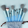 A collection of blue and silver makeup brushes with soft synthetic bristles displayed on a gray cloth.