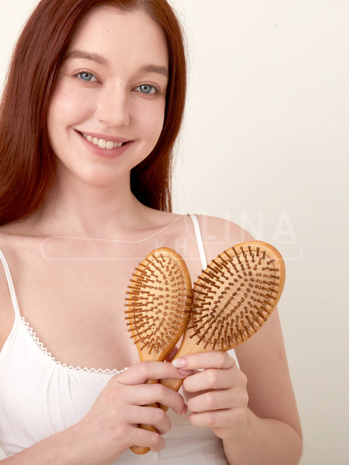 A woman holds a natural bamboo hair brush, demonstrating its use for detangling and scalp massage.
