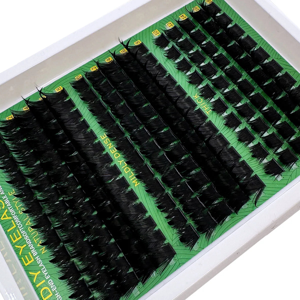 A tray of thick spiky cluster eyelash extensions in black and green packaging.