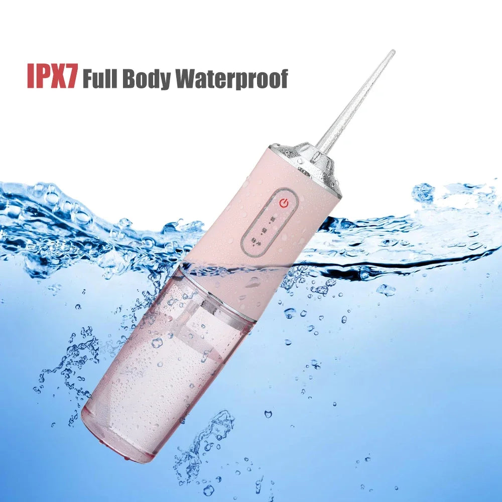 A pink portable oral irrigator device is shown submerged in water, demonstrating its IPX7 waterproof feature.