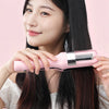 A woman holds a pink automatic hair ends trimmer against her long dark hair.