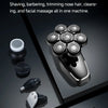 A close-up view of a black electric grooming device with five interchangeable blade heads resting on a dark surface.