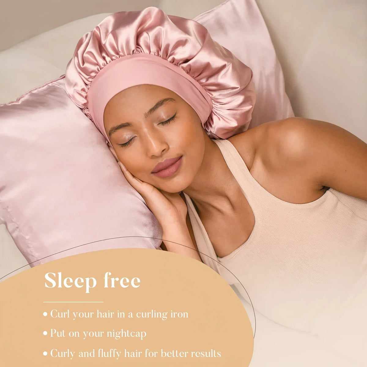 A woman wearing a pink satin bonnet and a pink satin hair cap, resting on a white pillow.