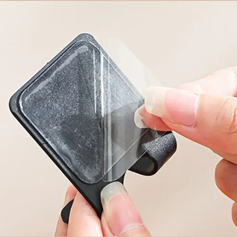 Une main tient un porte-support de rasoirs fixé au mur noir avec une housse de protection transparente.