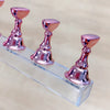 Un ensemble de supports à ongles magnétiques roses métalliques sur une base en acrylique clair.