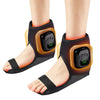 A pair of black ankle foot massagers with orange accents are shown on a person's feet.