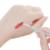 A hand is using a thin brush to apply red pigment onto the skin for lip or eyelash extensions.