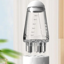 Applicateur pour cuir chevelu en verre transparent à cinq fonctions avec plusieurs embouts de pipette sur une base blanche.